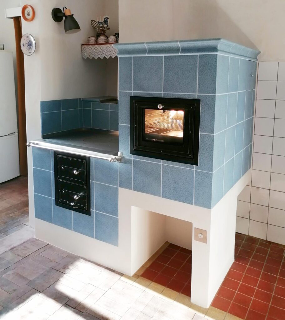 Tradiční kuchyňský sporák na dřevo s kováním Pertinger a kachlemi Kaufmann Keramik v jihočeské vesničce. První sporák s kobkou, kde jsme si vyzkoušeli osvětlení trouby. Foto zdroj: Jihočeské kamnářství